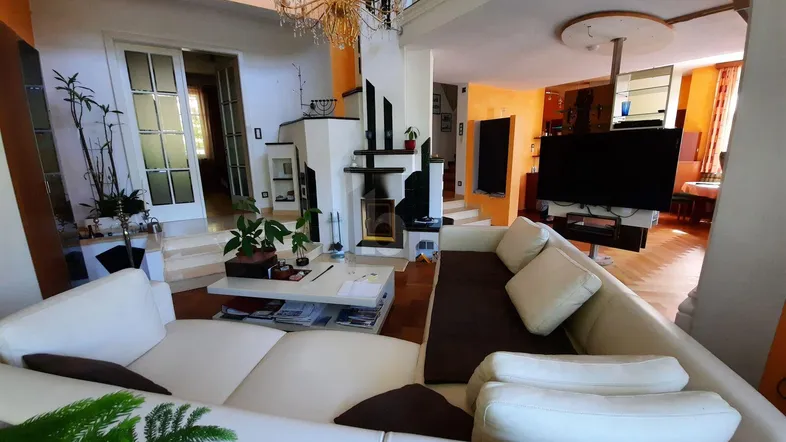 Geräumiges Wohnzimmer mit hohen Decken, großer Couch und modernem Unterhaltungssystem.