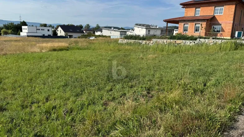 Grünfläche mit Baulandpotenzial und Blick auf umliegende Häuser und die weite Landschaft.