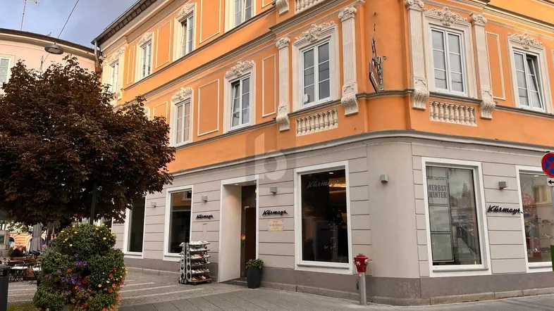 Historisches Eckgebäude mit orangefarbener Fassade und Geschäften im Erdgeschoss an einer städtischen Straße.