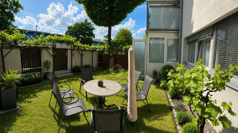 Gepflegter Gartenbereich mit Rasenfläche, Sitzgelegenheiten und üppigem Grün.