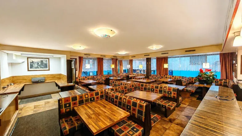Großer Gastraum mit zahlreichen Tischen und Sitzbänken, ideal für ein Restaurant oder eine Gaststätte.