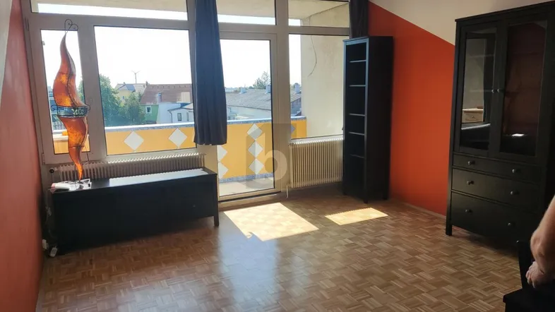 Helles Zimmer mit Parkettboden, orangefarbenen Wänden und direktem Zugang zu einem Balkon.