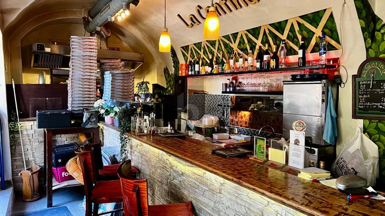 Gemütlicher Restaurantbereich mit einer Bar, Steinverkleidung und einem sichtbaren Pizzaofen im Hintergrund.