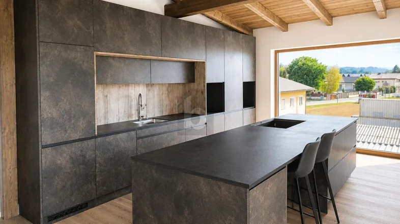 Moderne Küche mit dunklen Schränken, Kücheninsel und Holzbalkendecke sowie großem Fenster.