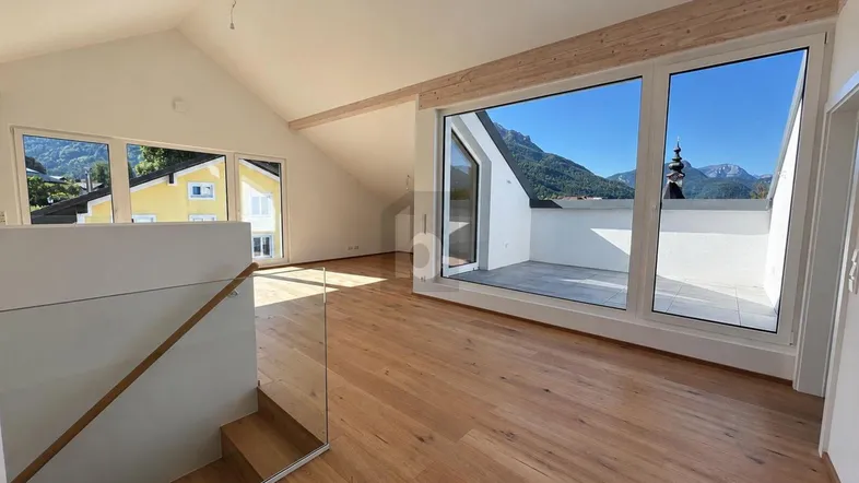 Helles, geräumiges Wohnzimmer mit Holzboden, sichtbaren Balken und Zugang zu einer Terrasse mit Bergblick.