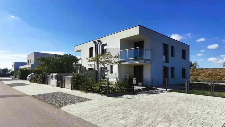 Modernes Einfamilienhaus mit Flachdach, Balkon und gepflasterter Auffahrt.