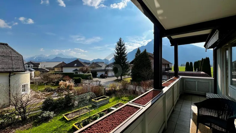 Geräumiger Balkon mit atemberaubendem Bergblick, umgeben von grünen Gärten und Häusern.