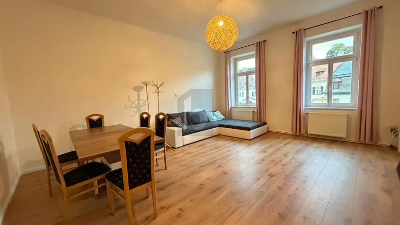 Heller Wohn- und Essbereich mit Holzboden, großem Esstisch und gemütlicher Sofaecke.