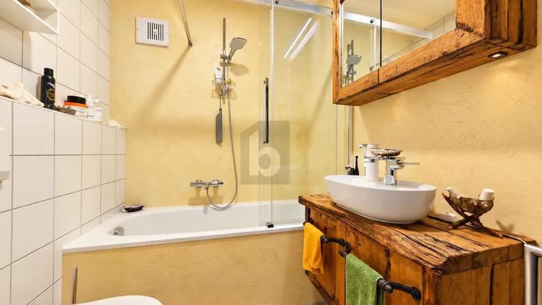 Modernes Badezimmer mit Badewanne, Duschabtrennung und rustikalem Holzwaschtisch unter einem Spiegelschrank.