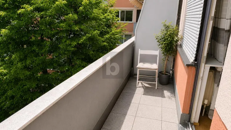 Schmaler Balkon mit Fliesenboden, einem Stuhl und Blick ins Grüne.