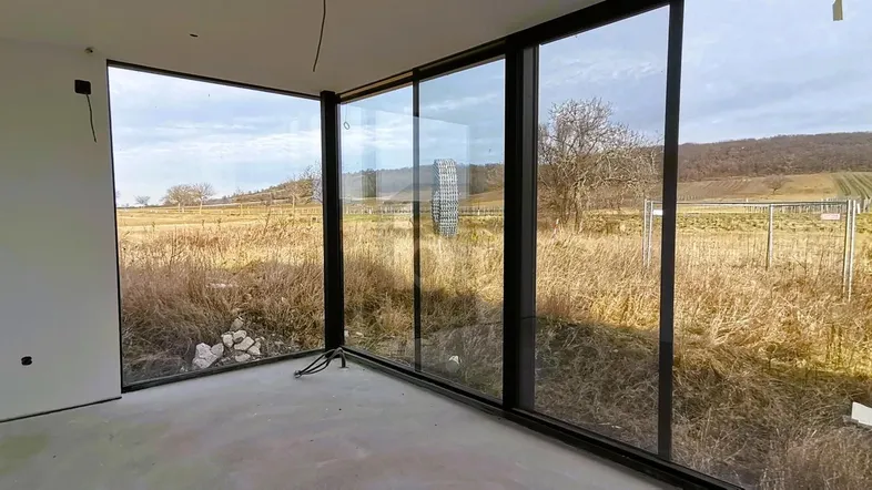 Heller Innenraum im Bau mit großen Fenstern und weitem Blick auf die Landschaft.