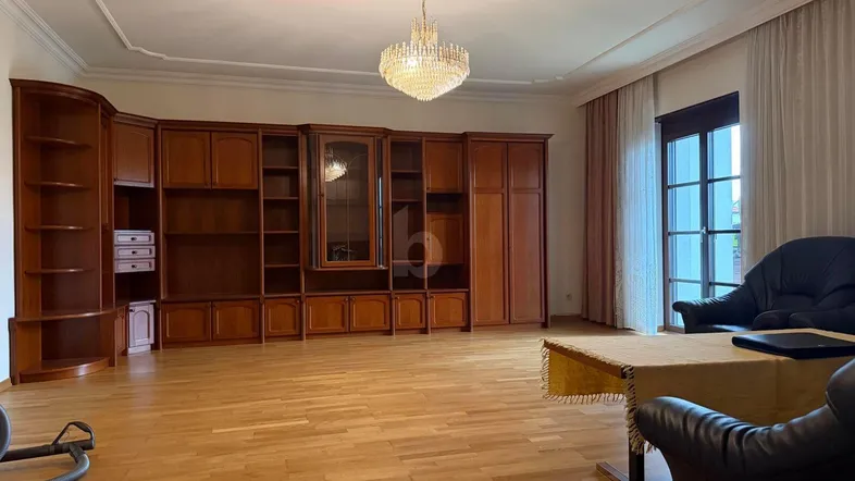 Geräumiges Wohnzimmer mit klassischem Holzschrank, Parkettboden und Kronleuchter, ideal für gesellige Abende.