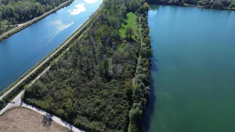 Luftaufnahme eines Grundstücks zwischen zwei Wasserläufen, umgeben von üppiger Vegetation und Bäumen.