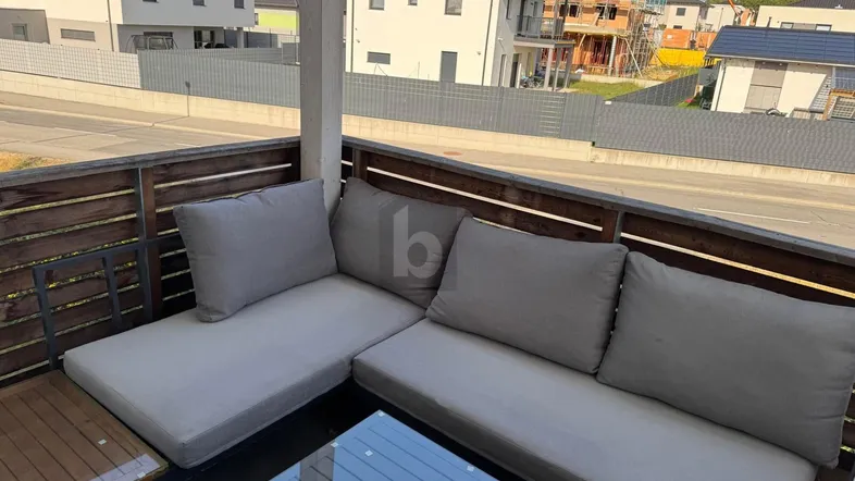 Möblierter Balkon mit bequemen Lounge-Möbeln und Blick auf die Nachbarschaft.