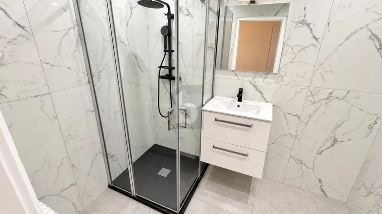 Modernes Badezimmer mit weißen Marmorfliesen, begehbarer Dusche und Einzelwaschbecken.