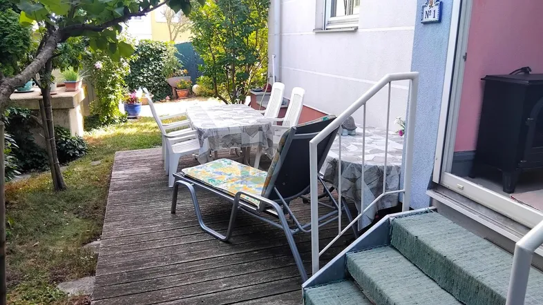 Holzterrasse mit Gartenmöbeln und Zugang zum grünen Gartenbereich, ideal für entspannte Stunden im Freien.