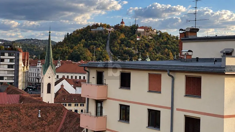 Panoramablick über die Stadt mit historischen Gebäuden, Kirchturm und einer Festung auf dem Hügel.