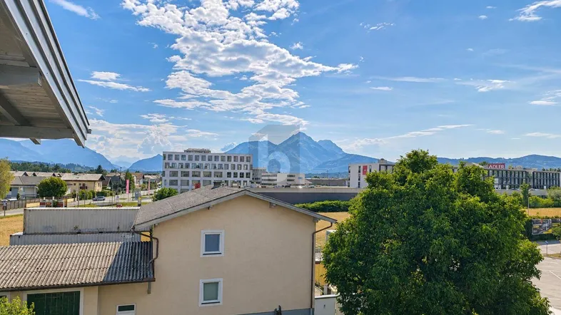 Panoramablick auf die Berge und die umliegende Bebauung von einem Balkon aus.