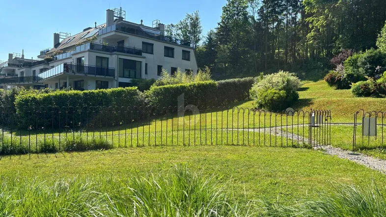 Moderne Wohnanlage mit mehreren Balkonen und Terrassen, umgeben von grüner Landschaft und Bäumen.