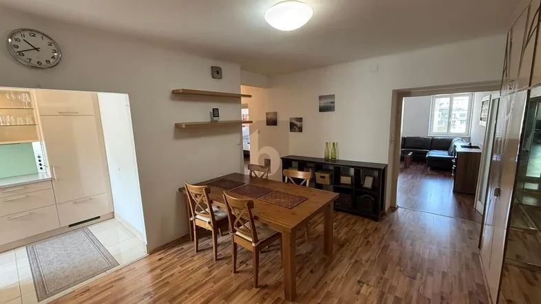 Heller Essbereich mit Holztisch und Blick in die Küche sowie das Wohnzimmer.
