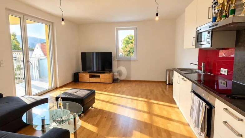 Heller offener Wohn- und Essbereich mit integrierter Küche und Zugang zum Balkon.