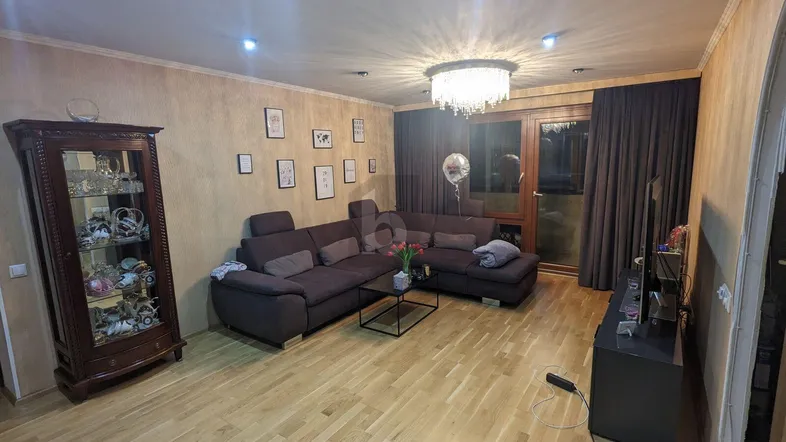 Geräumiges Wohnzimmer mit Ecksofa, Holzboden und dekorativer Beleuchtung, ideal für entspannte Abende.