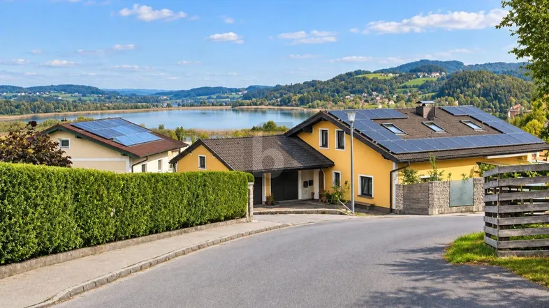 Gelbes Haus mit Solaranlagen und herrlichem Blick auf den See und die umliegende Berglandschaft.