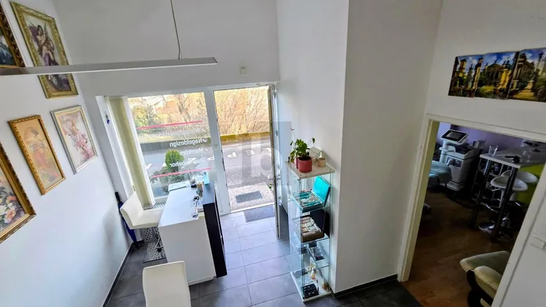 Heller Eingangsbereich mit hohen Decken, Fliesenboden und Blick zur Straße.