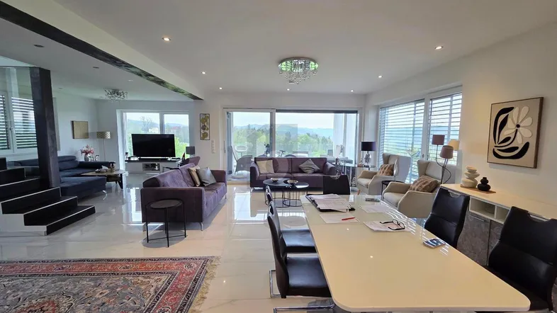 Helles, offenes Wohn-Esszimmer mit modernen Möbeln, glänzendem Fliesenboden und Zugang zur Terrasse.