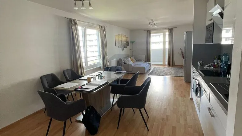 Heller offener Wohn- und Essbereich mit integrierter Küche und Zugang zum Balkon.