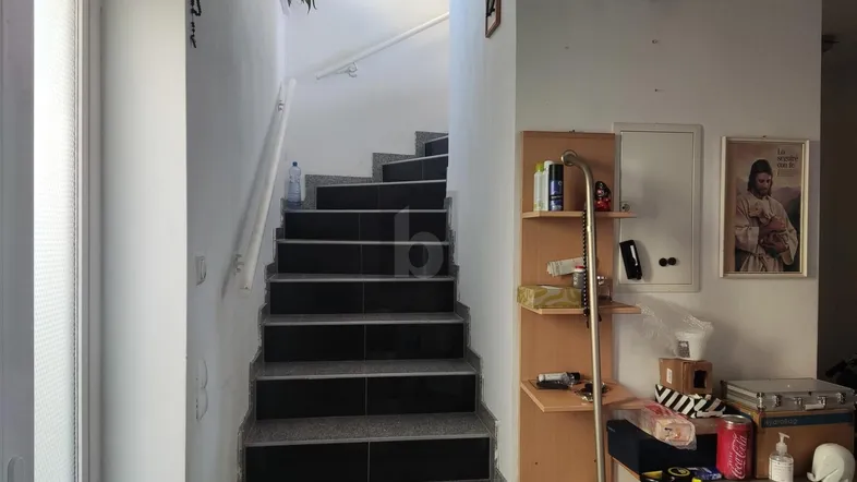 Treppenhaus mit dunklen Fliesenstufen und hellem Geländer, das zu den oberen Etagen führt.