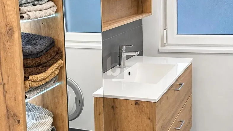 Modernes Badezimmer mit Holzwaschtischunterschrank, Spiegelschrank und Fenster für Tageslicht.