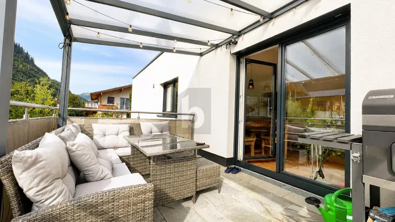 Geräumige überdachte Terrasse mit gemütlicher Sitzgruppe, Grillbereich und Blick auf die umliegende Natur.