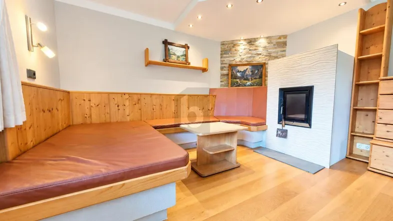 Gemütliches Wohnzimmer im alpinen Stil mit Holzbänken, Kaminofen und Holzboden.