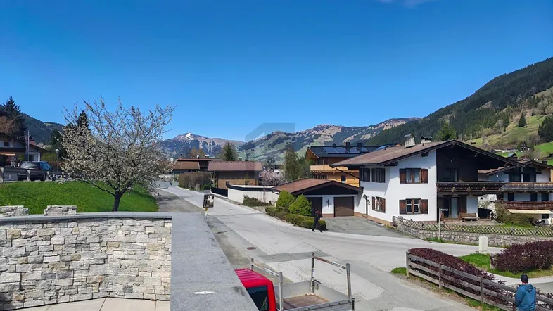 Panoramablick auf die umliegende Berglandschaft und traditionelle Häuser in sonniger Lage.