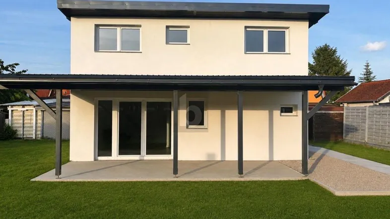 Modernes Einfamilienhaus mit heller Fassade, Flachdach und überdachtem Eingangsbereich.