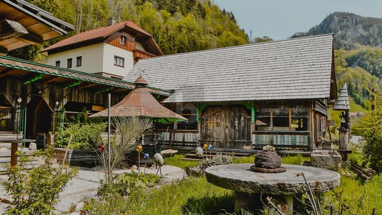 Traditionelles Holzhaus mit Satteldach und gepflegtem Garten in alpiner Umgebung.