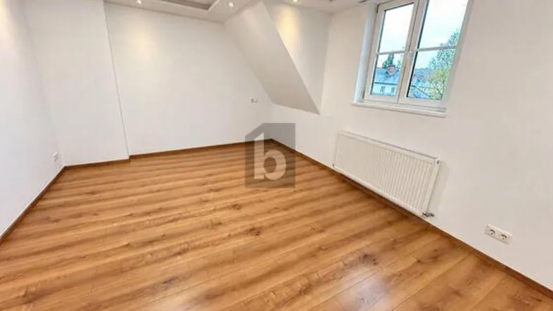 Helles Zimmer mit Laminatboden und Dachschräge, ideal als Schlaf- oder Wohnbereich.
