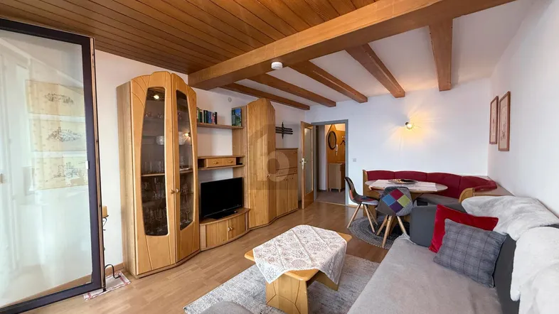 Gemütlicher Wohn- und Essbereich mit Holzbalkendecke und traditionellen Holzmöbeln.
