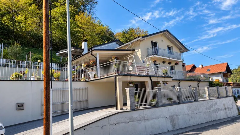Attraktives Haus mit mehreren Balkonen, einer Auffahrt und umzäuntem Grundstück in grüner Umgebung.