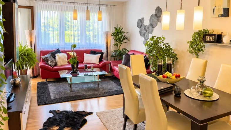 Heller Wohn- und Essbereich mit Parkettboden, roten Sofas und modernem Dekor.