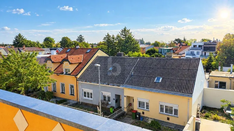 Blick über die Dächer der Nachbarschaft mit sonnigem Himmel und umliegender Bebauung.