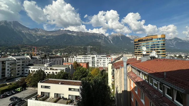 Panoramablick über die Stadt mit majestätischen Bergen im Hintergrund und städtischer Architektur.