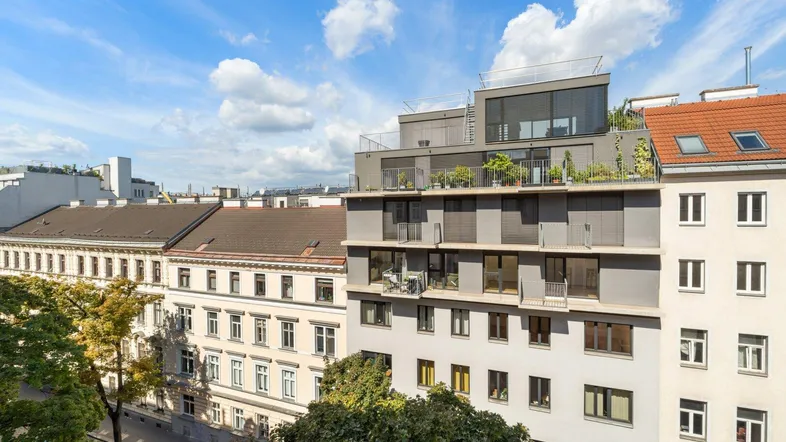 Blick auf moderne und klassische Gebäude mit Dachterrassen unter blauem Himmel.