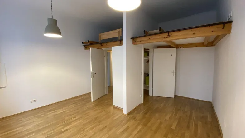 Zimmer mit Holzboden, hohen Decken und einer Holzkonstruktion für eine Schlafgalerie.