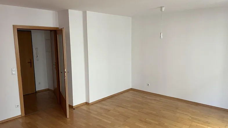 Helles Zimmer mit Parkettboden und weiß gestrichenen Wänden, bereit zur individuellen Gestaltung.