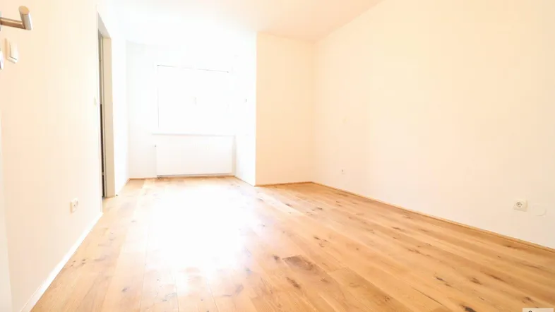 Helles, leeres Zimmer mit neuem Eichenparkettboden und weißen Wänden, bereit zur Einrichtung.