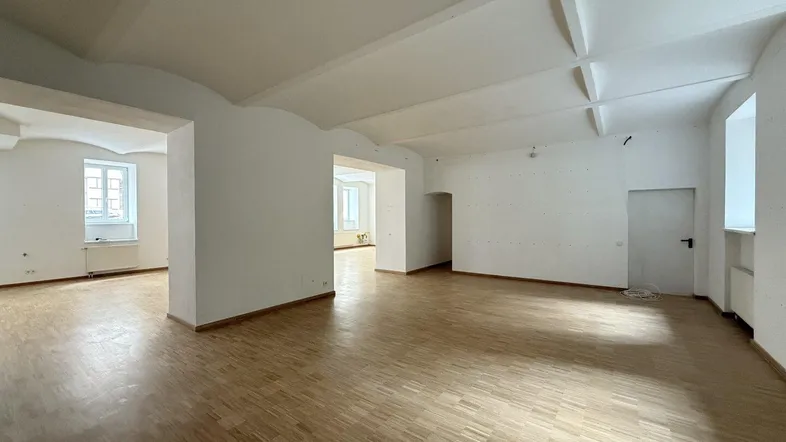 Heller, weitläufiger Raum mit Holzboden und hohen Decken, ideal für flexible Nutzung.