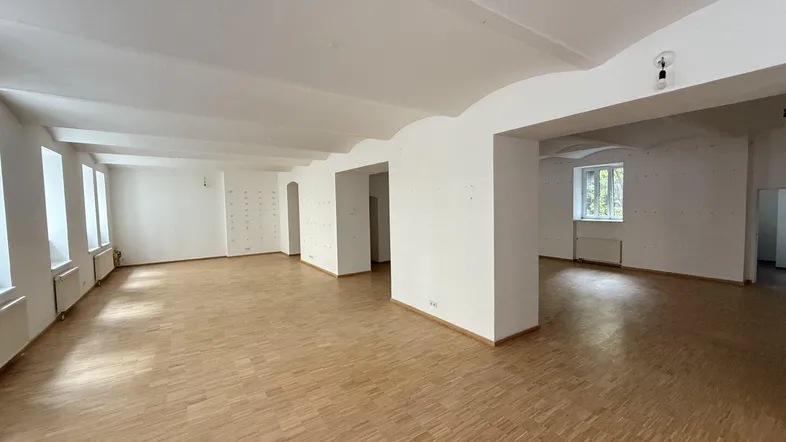 Großer, heller Raum mit vielen Fenstern und Holzboden, bereit für individuelle Gestaltung.