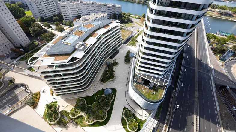 Luftaufnahme des modernen Gebäudekomplexes mit geschwungenen Formen und begrünten Dächern.